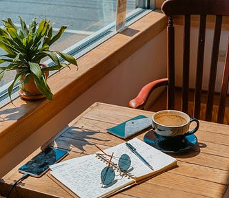 experts take on editing. A writing notebook, coffee cup on a small writing desk. It is a roadside cafe.