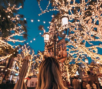 A woman surrounded by Christmas cheer and lights.