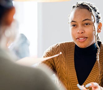 Young woman holds paper in interview or other professional setting.