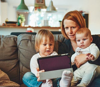 Mother watching an iPad with two children: a todler and a baby
