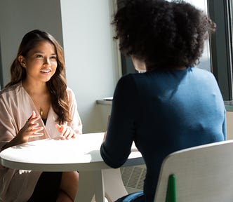 Two women sitting at a table and having a conversation.