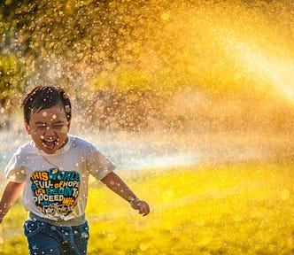What’s the Real Difference Between Motivation and Inspiration? A child runs happily through a sprinkler.