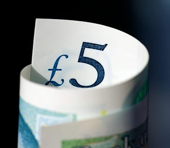 A closeup of a five pound note rolled up.