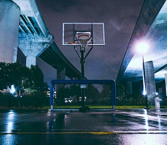 basketball hoop under a bridge at night