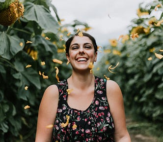 A woman smiles as she is showered with flower petals