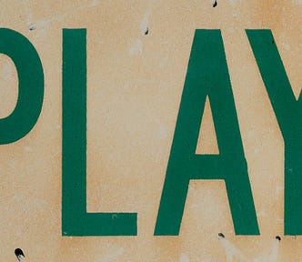 The word PLAY in large green, block letters on a tan background.