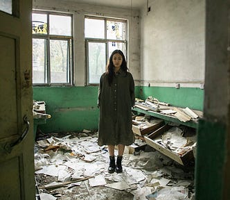Woman standing in an abandoned room, strewn with papers