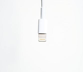 An Apple lightning cable on an off-white background.