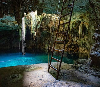 Ladder nearby an underground pool of blue water in a cave.