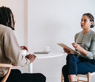 Two people sitting at the table, one person asking question to the other