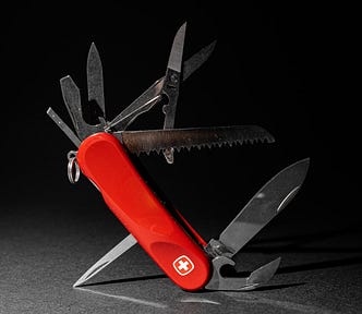 Photo of red pocket knife multi-tool propped up at a 45˚ angle, with all its tools extended at different angles