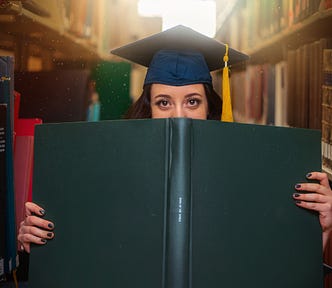 woman in library face half hidden by a book