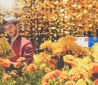 Image of male reading a Dr. Seuss book surrounded by flowers.