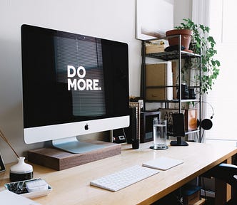 desk with a monitor that says Do More