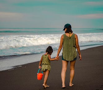 mother and daughter walk down the beach