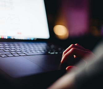 An up-close view of a laptop with a bright screen glowing in the dark, representing a deeper truth search in the dead of night.