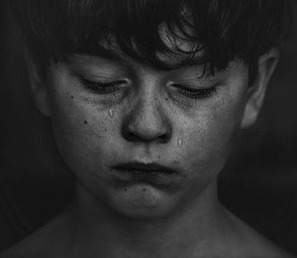 A black and white close-up of a young boy crying.