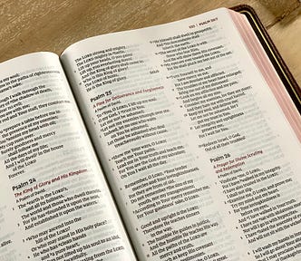 A Bible open to the Psalms. Psalm 24, 25, and 26 are visible on the page.