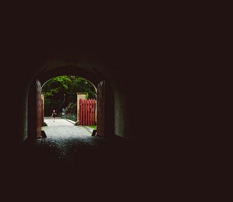 Black room with a doorway open, light shining in and a path