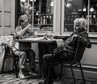 Two elderly women having drinks at a table