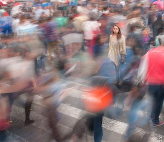 A young woman (just to the right of center) is clear. She is surrounded by numerous blurred shoppers.