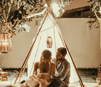 couple eating outside under romantic lights and a tent