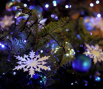 Blue Christmas tree ornaments on a branch with big white snowflakes