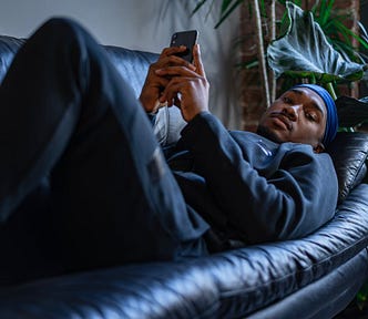 A Man Lying on a Sofa Holding a Cell Phone