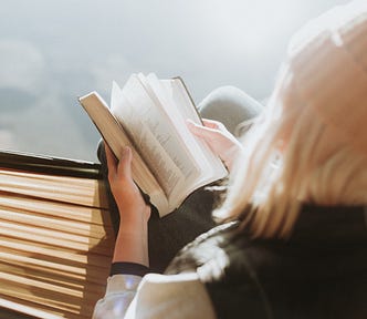 woman with blond hair reading a book in the sunshine