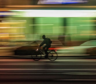 Blurred photo of bicycle rider along a busy night-time street