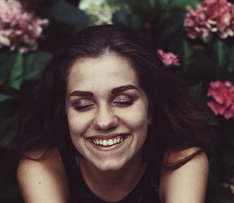 A happy woman smiles in a garden of flowers
