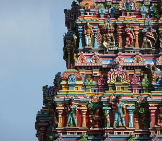 Picture of an entrance tower in a Hindu temple sporting sculptures of deities and mythical beings