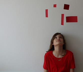 A woman in a red dress thinks aloud. Her thoughts appear above her head as red blocks.
