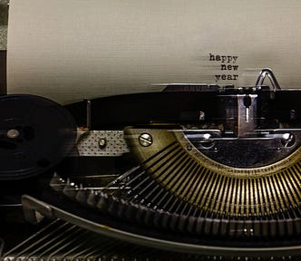 Old typewriter with typed “happy new year” on the blank white page.