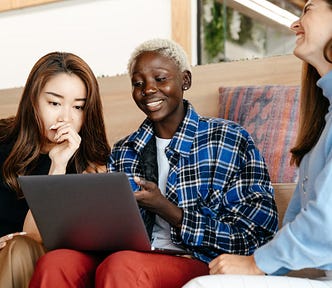 Cheerful multiethnic colleagues browsing internet on laptop