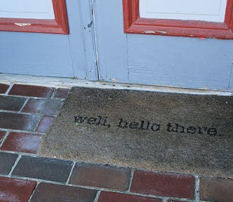 A welcome mat on a step outside the front door of a house.