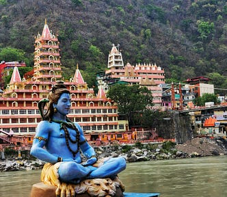 Image of the Ganges River with a statue of a blue god in the foreground.