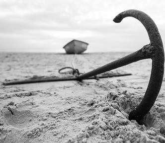 An anchor on a beach in black and white