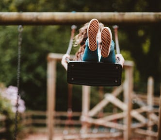 A girl on a swingset — the image shows the bottom of her feet on the upswing