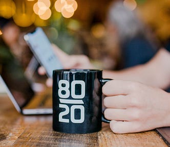 A coffee mug on a table with 80 and 20 written on it.