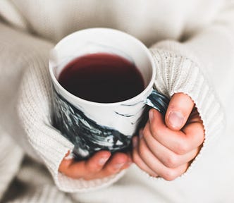 Woman holding mug of coffee with her jumper sleeves over her hands