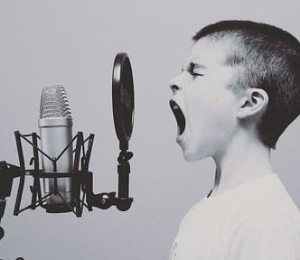 A boy talks into a microphone at full blast