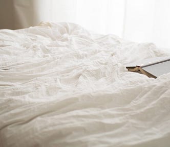 crumpled bedsheets and an open book