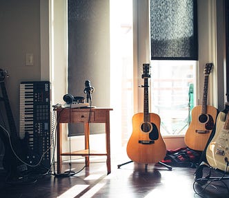 Home music studio with recording gear including guitars, keyboards, and mics.