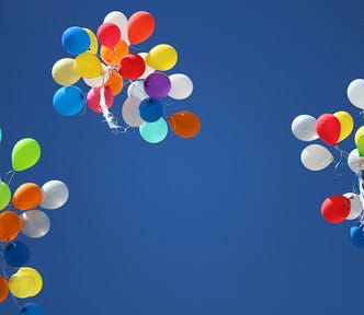 Three bunches of coloured balloons in the sky