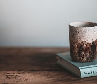 Wabi Sabi book with natural material cup on wooden bench