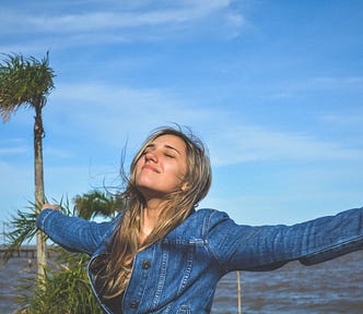 woman with raise arms smiling content with life
