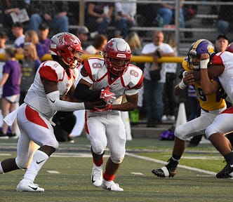 Two American football players on the field passing the ball to each other