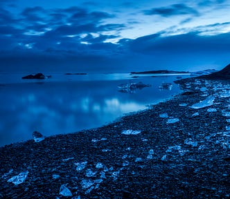 An icy beach, very blue image in low light