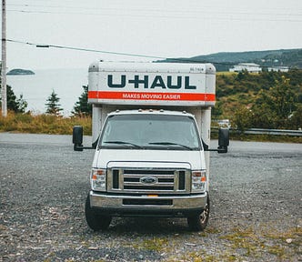 A U-Haul truck off the side of a highway facing the viewer.